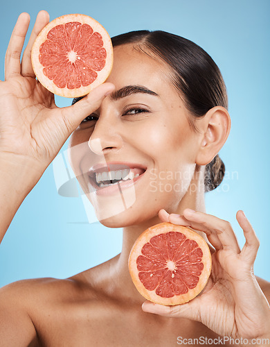 Image of Portrait, face and skincare of woman with grapefruit in studio isolated on a blue background. Organic cosmetics, food and female model with fruits for nutrition, healthy diet or vitamin c for beauty.