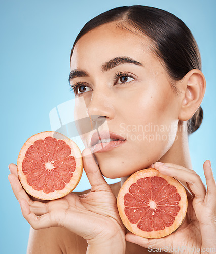 Image of Face, beauty and skincare of woman with grapefruit in studio isolated on a blue background. Organic cosmetics, food and female model thinking about fruits for nutrition, healthy diet or vitamin c.