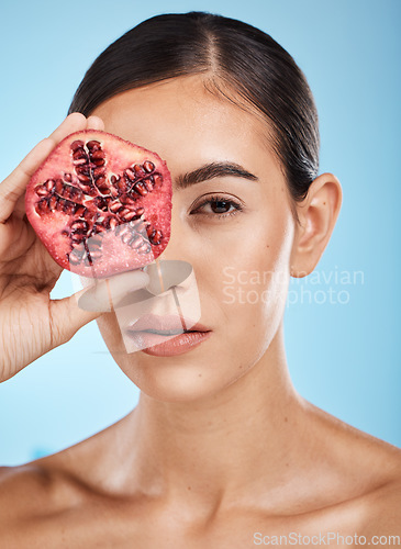 Image of Skin care, beauty and woman portrait with pomegranate fruit face for dermatology and cosmetics. Aesthetic model person for natural product facial glow, nutrition and healthy diet on blue background