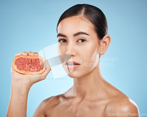 Image of Face, beauty and grapefruit squeeze woman portrait for dermatology, natural cosmetic and wellness. Aesthetic model person for vitamin c fruit facial glow, nutrition diet and skin care blue background