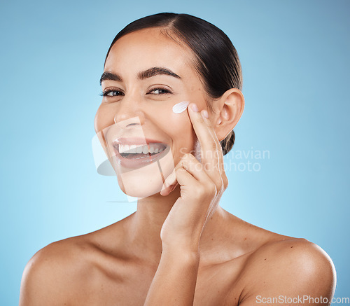 Image of Portrait, beauty and cream with a model woman in studio on a blue background for natural skincare. Face, lotion and cosmetics with an attractive young female posing to promote a skin product