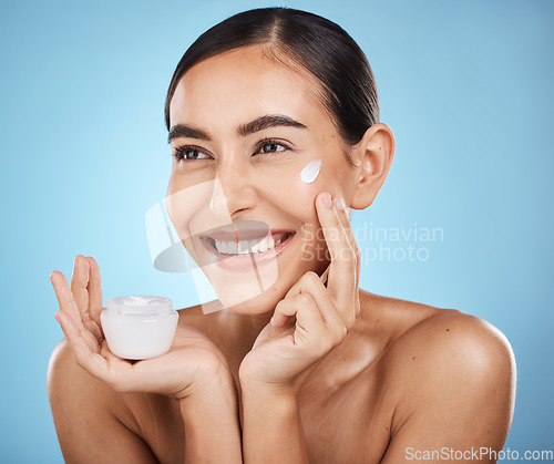 Image of Face, cream and skincare product of woman in studio isolated on a blue background. Cosmetics, aesthetics and happy female model thinking about lotion, creme or moisturizer for beauty and wellness.