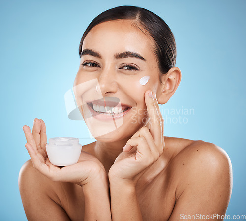 Image of Face cream, skincare portrait and woman with product in studio isolated on a blue background. Cosmetics, dermatology and happy female model with lotion, creme or moisturizer for beauty and wellness.