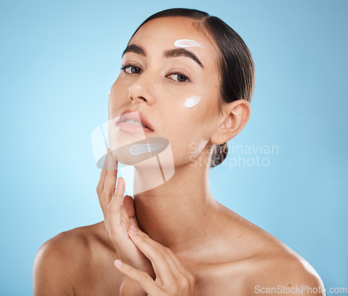 Image of Skincare cream, face portrait and woman in studio isolated on a blue background. Cosmetics, dermatology and young female model with lotion, creme or moisturizer for beauty, aesthetics and wellness.