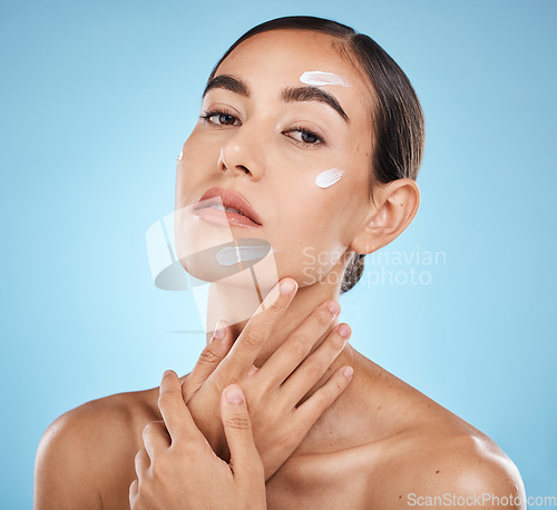 Image of Face portrait, skincare cream and woman in studio isolated on a blue background. Cosmetics, dermatology and young female model with lotion, creme or moisturizer for beauty, aesthetics and wellness.