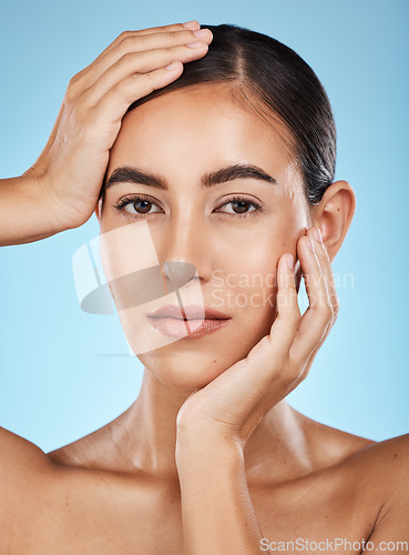 Image of Portrait, beauty and hands with a model woman in studio on a blue background for natural skincare. Face, skin and cosmetics with an attractive young female posing to promote a luxury product