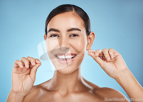 Image of Woman, flossing in portrait and smile, dental healthcare for fresh breath and clean teeth isolated on blue background. Face, hands and flossing with oral hygiene product and healthy gums in studio