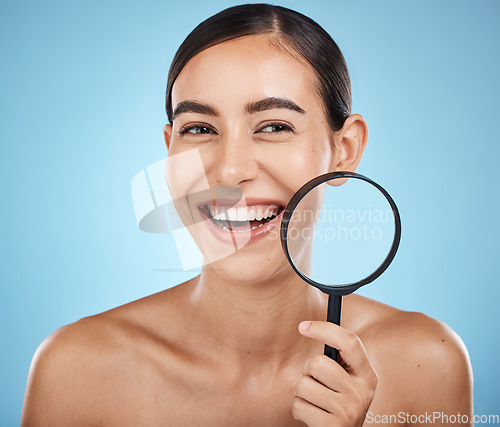 Image of Face skincare, magnifying glass and beauty of woman in studio isolated on a blue background. Facial portrait, makeup and cosmetics of female model with magnifier lens to check aesthetic wellness.