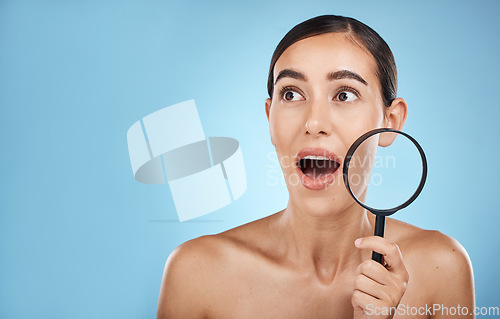 Image of Woman, face and surprise with magnifying glass, beauty and acne with skin problem isolated on blue background. Skincare cosmetics, wow and facial inspection, mockup space and dermatology in studio