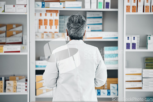 Image of Stock, back and pharmacist at a medicine shelf for healthcare, medical work and service at a pharmacy. Doctor, pills and pharmaceutical worker looking at the coice of drugs while working at a clinic