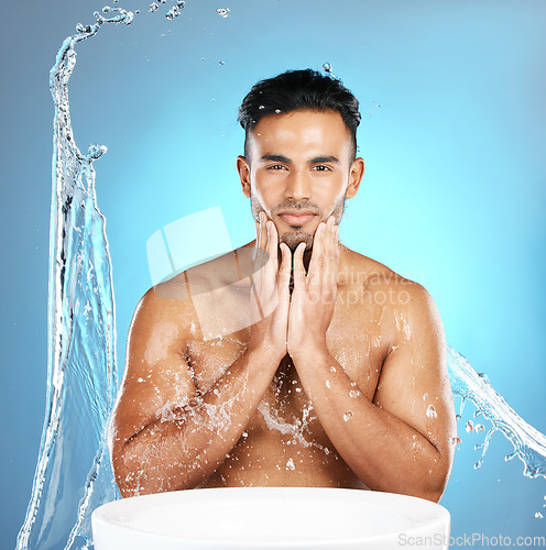 Image of Water splash, face and man with basin for beauty, skin and skincare cleaning body and topless. Mexican, male and wellness model with moisture, cleanse and hydration isolated in studio blue background