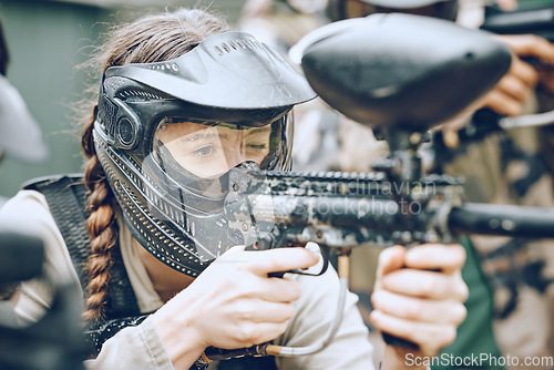 Image of Paintball, gun and woman with helmet aim for shooting ready for game, arena match and battlefield. Extreme sports, military adventure and girl with weapon in camouflage, action and safety gear