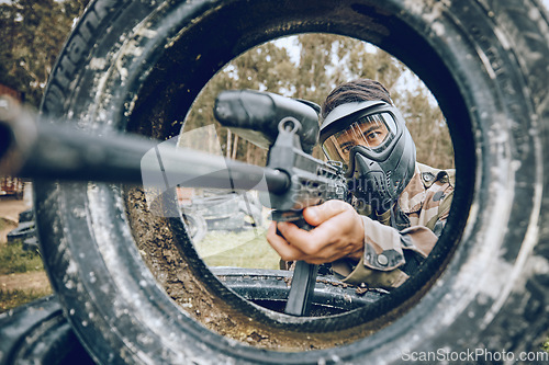 Image of Gun aim at target with tire, paintball and man outdoor, action on battlefield and soldier focus during war game. Extreme sport, weapon and military mission, exercise and fitness with determination