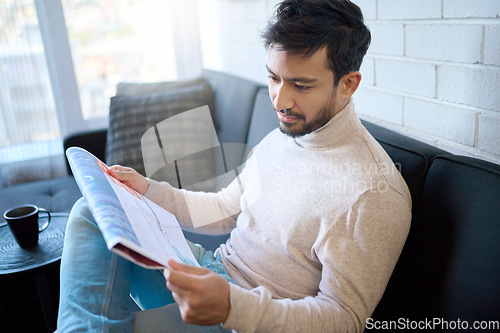 Image of News, newspaper and man reading article in a home, house or apartment on the weekend sitting on a couch or sofa. Mexican, relax and young person enjoying free time in living room in the morning