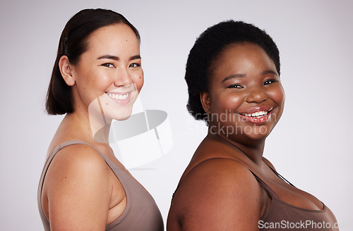Image of Portrait, black woman and Asian girl with skincare, friends and smile with confidence, cosmetics and body care on grey studio background. Face, diversity and females with happiness and dermatology