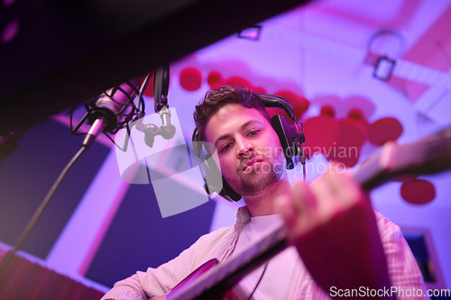 Image of Man, musician or guitar in neon studio, recording production or live performance for radio, label or low angle audio. Guitarist, artist or person playing strings instrument on headphones in practice