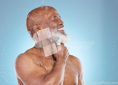 Image of Water, splash and beauty with black man and shower for skincare, hygiene and dermatology. Wellness, spa and facial with senior model cleaning in blue background studio for health, luxury or hydration