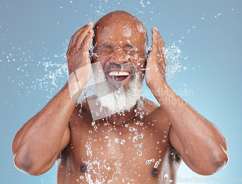 Image of Water splash, beauty and black man isolated on blue background for face cleaning, beauty and hands skincare. Happy senior model or person with facial wash or hygiene for dermatology in studio action