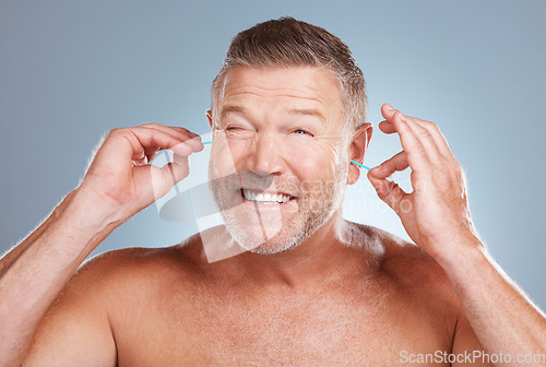 Image of Earbuds, grooming and man cleaning his ears in a studio for self care, hygiene and cleanliness. Health, wellness and mature guy doing his morning body care routine isolated by a gray background.