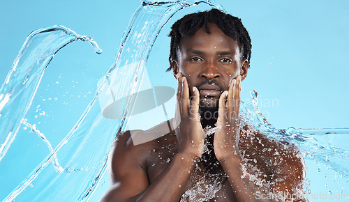 Image of Water splash, facial skincare and portrait of black man with hands on face, morning cleaning isolated on blue background. Hygiene, male model and grooming for health, wellness and skin care in studio