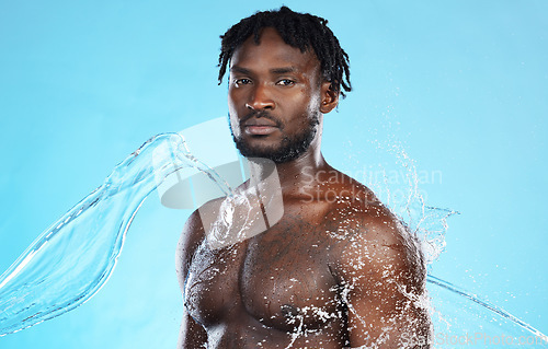 Image of Skincare, shower and portrait of a black man with a water splash isolated on a blue background. Cleaning, beauty and African model for grooming, hygiene and care of body on a studio backdrop