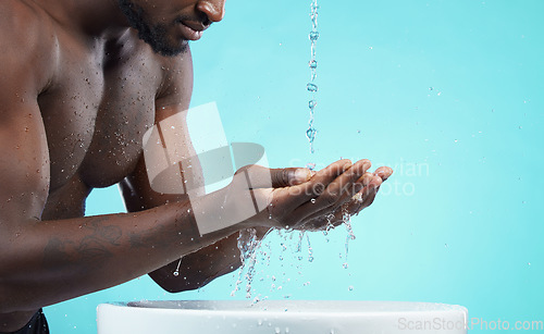 Image of Water drops, black man and cleaning hands with skin, washing face and skincare isolated on blue background. Mockup space, clean body and natural cosmetics with grooming, hygiene and beauty in studio