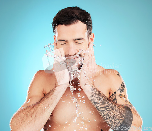 Image of Water splash, skincare and man with hands on beard, morning cleaning treatment isolated on blue background. Facial hygiene, male model and grooming face for health, wellness and skin care in studio.