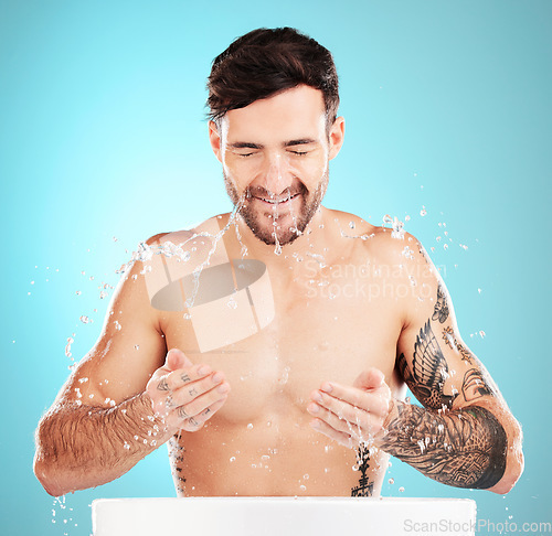 Image of Water splash, facial skincare and man with cleaning face, morning detox treatment isolated on blue background. Hygiene, male model and grooming for health, wellness and skin care or beauty in studio.