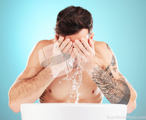 Image of Water, skincare and man with hands on face, morning cleaning treatment isolated on blue background. Facial hygiene, splash and male model grooming for health, wellness and clean skin care in studio.