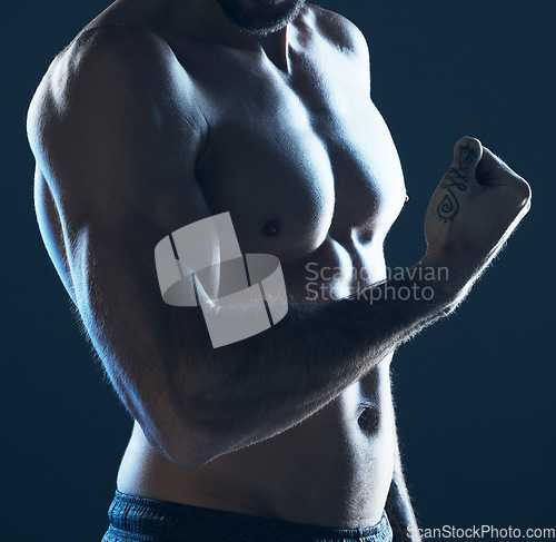 Image of Fitness, body and man flexing arm on blue background, isolated, neon blue light and muscular chest. Sports, muscle and topless male model in artistic dark studio for power workout and gym aesthetic.