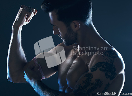 Image of Muscle, showing and man with arms in the dark for fitness isolated on a studio background. Exercise, training and muscular bodybuilder flexing a bicep for workout results, performance and progress