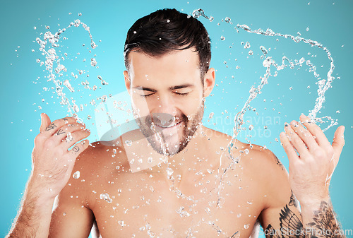 Image of Water, skincare and man with facial splash, smile and morning cleaning treatment isolated on blue background. Face, hygiene and male model grooming for health, wellness and clean skin care in studio.