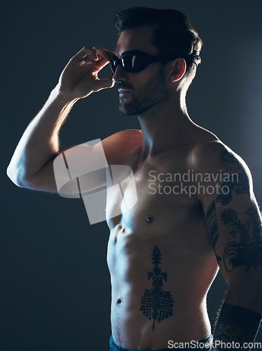 Image of Sports, fitness and body of swimmer in studio with goggles for wellness, exercise and swimming training. Workout, motivation and man athlete on dark background with muscle, strong body and tattoo