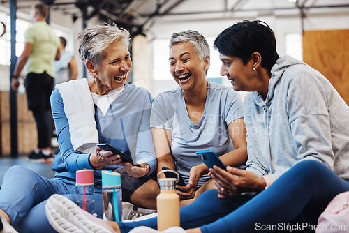 Image of Gym, smartphone and senior women laughing at meme on phone after fitness class, conversation and comedy on floor. Exercise, bonding and happy mature friends checking social media together at workout.