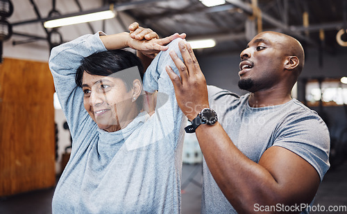 Image of Personal trainer, coach and senior woman stretching arms in gym with black man for flexibility. Sports, training and elderly female with male trainer helping with workout and exercise for health.