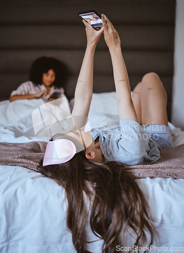 Image of Video call, phone and relax with woman at sleepover for communication, internet and contact. Happy, online dating and smile with girl and friends in bedroom with technology, digital and social media