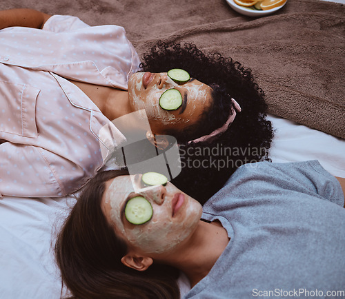 Image of Facial, cucumber and sleepover with girl best friends lying on the floor together for beauty treatment. Face mask, skincare or natural care with a female and friend at home to relax while bonding