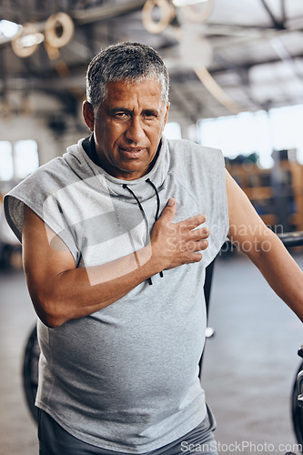 Image of Fitness, gym and old man with pain in chest, medical emergency during workout at sports studio. Exercise, health and wellness, stress and tired senior person with hand on heart muscle while training.