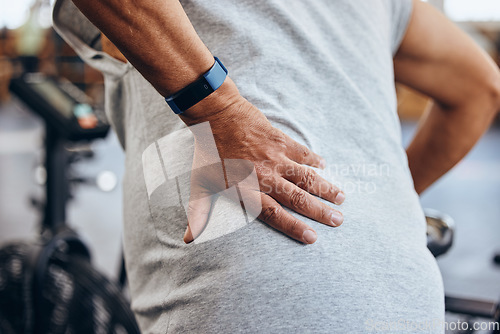 Image of Fitness, gym and old man with hand on back pain, emergency during workout at sports studio. Health, wellness and inflammation, zoom on senior person hands on muscle cramps while training or exercise.