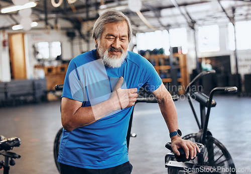 Image of Fitness, gym and old man with pain in chest, medical emergency during workout at sports studio. Exercise, health and wellness, stress and asian senior person with hand on heart muscle while training.