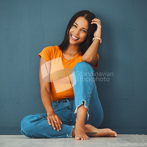 Image of Black woman, floor and home with smile by wall for clothes, relax and fashion with barefoot. Gen z girl, model portrait and happy in house with feet, jeans and happiness on face by blue background