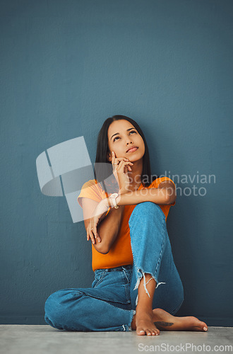 Image of Woman on ground, thinking and decision for opportunity, ideas and girl daydreaming on blue studio background. Female with imagination, lady on floor and wondering with focus, mindset and thoughts