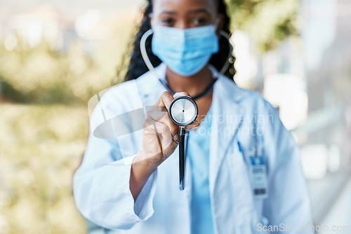 Image of Covid, doctor and stethoscope at hospital with mask for compliance, safety and healthcare on bokeh background. Checkup, corona and female health expert at clinic for help, goal and innovation outside