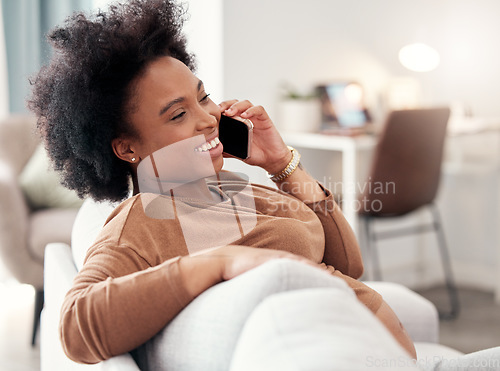 Image of Phone call, relax and smile with a black woman in the living room of her home, sitting on a sofa while talking. Mobile, communication and conversation with a young female chatting in her house