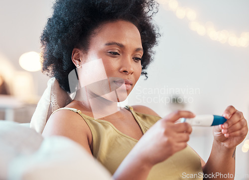 Image of Black woman, pregnancy test and confused, nervous and waiting for results on a sofa in her home. Pregnant, testing and female unsure, doubt and holding result, checking and reading in a living room