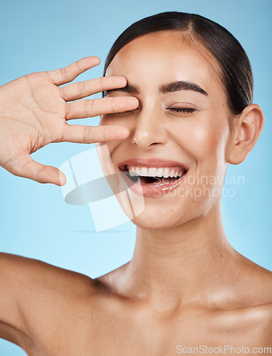 Image of Skincare, beauty and face of woman on blue background for self care, wellness and cosmetics in studio. Spa aesthetic, dermatology and hand of girl smile for facial treatment, salon and healthy skin