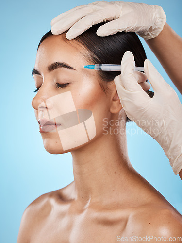 Image of Skincare, botox and woman in a studio with a beautician for face filler, cosmetic and plastic surgery treatment. Beauty, cosmetology and female model getting a facial injection by a blue background.