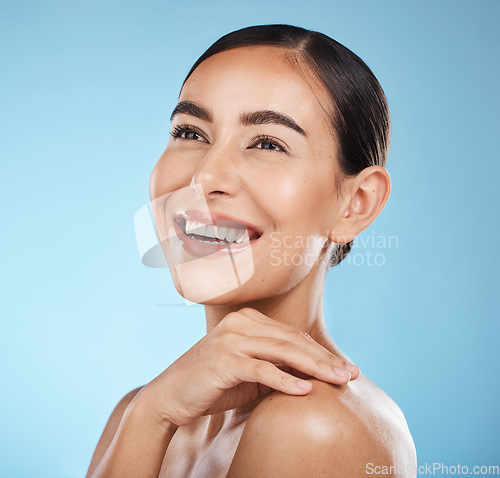 Image of Woman, face and smile, happy and beauty with natural cosmetics and glow isolated against blue background. Clean, cosmetic care and hand with facial, makeup and healthy skin with skincare in studio
