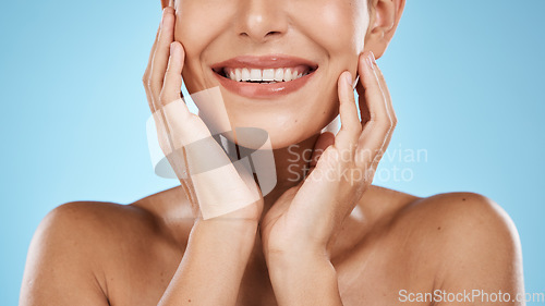 Image of Skincare, facial and smile of woman on blue background for luxury, wellness and cosmetics in studio. Spa aesthetic, dermatology and mouth of girl with hands for beauty, treatment and healthy skin