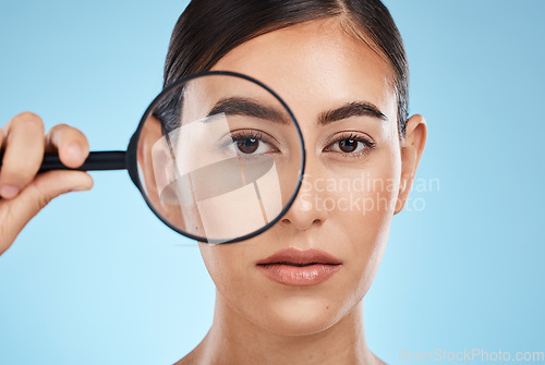 Image of Woman, face with magnifying glass, eyes and beauty in portrait, eye care and vision isolated on blue background. Skincare cosmetics, skin and facial inspection, mockup space and dermatology in studio